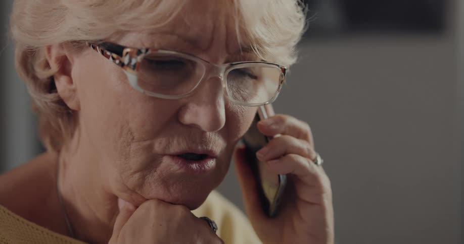 Senior citizen wearing glasses talking on the phone at home