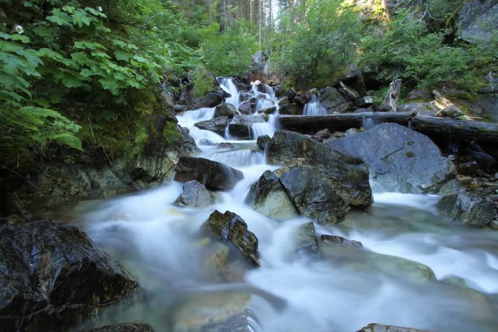 Water flowing over a rocky river bed in time lapse during the day