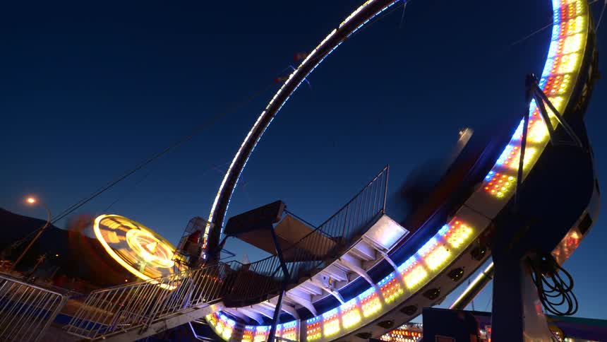 Time lapse of carnival rides flashing lights at dawn