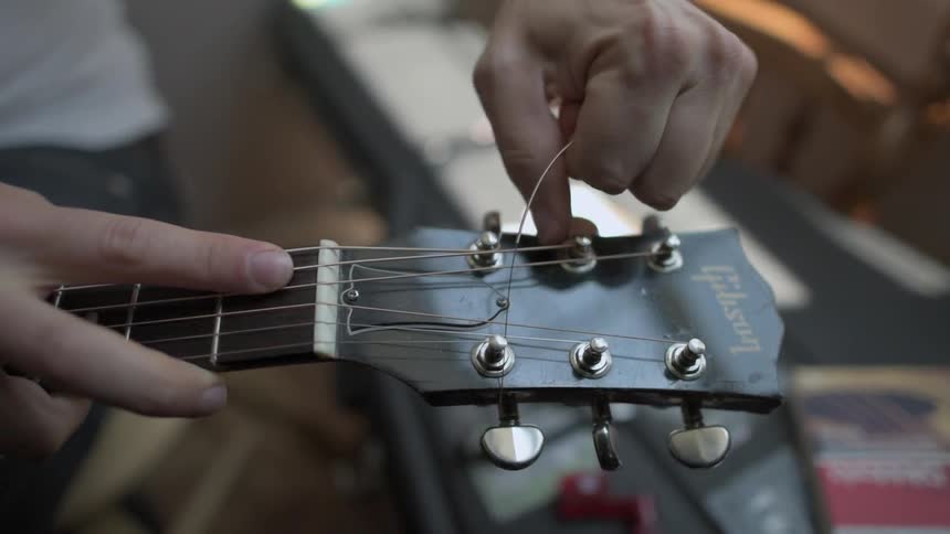 Close up of a person's hands stringing a guitar
