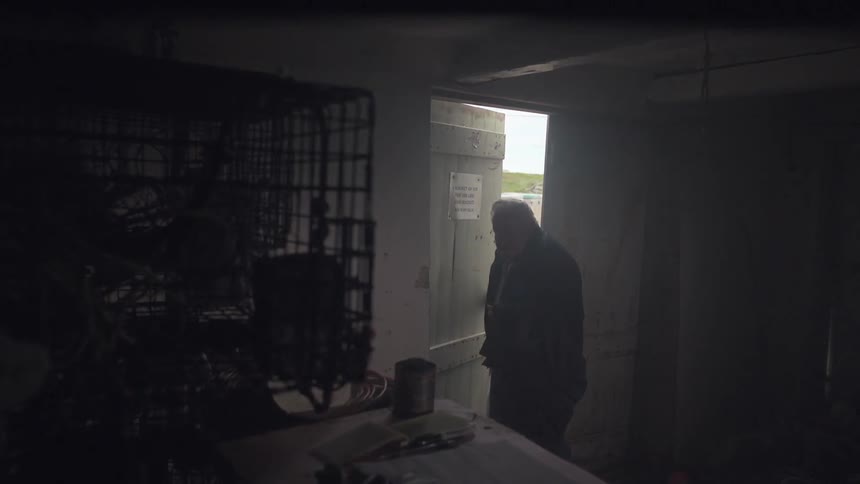 An older man walks into a dimly lit room