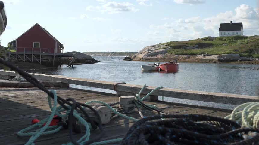 Ropes cover a river dock with two boats floating in the background
