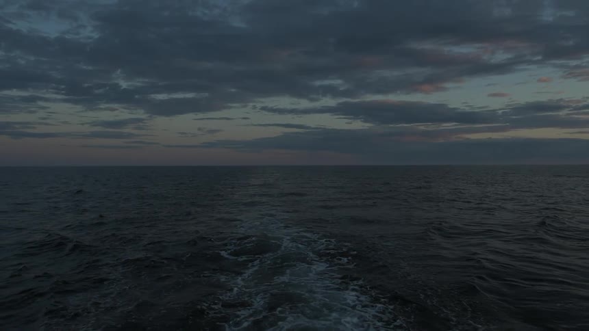 A trail of white in a body of water near dusk