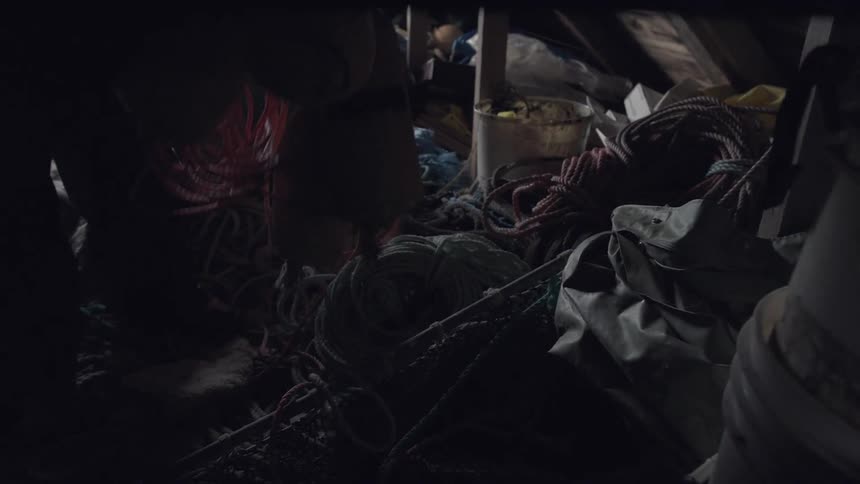 A person lifts up some items from a cluttered floor