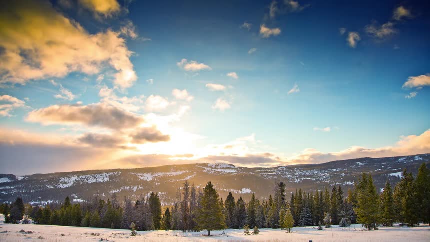 Clouds pass over a snowy mountain scene