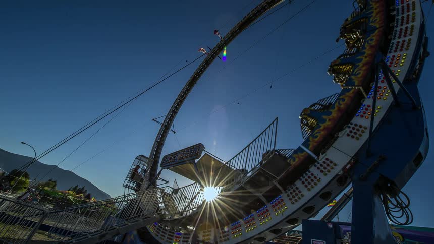Time lapse of carnival rides flashing lights at sunset