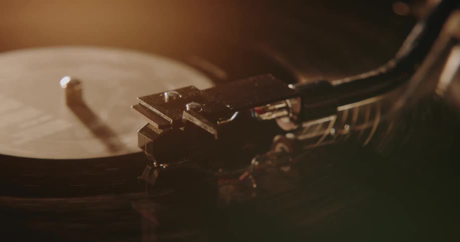 A vinyl record is spinning on an old turntable and the needle arm moves away
