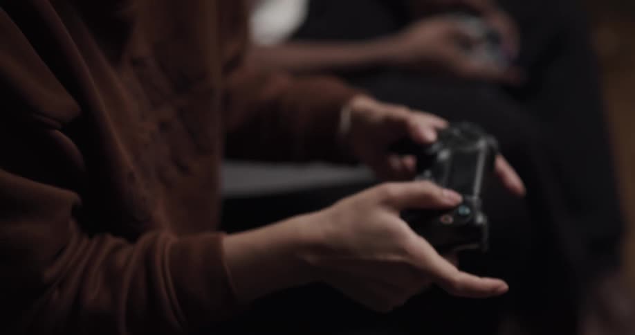 A young woman plays video games with a man while they sit together on a sofa