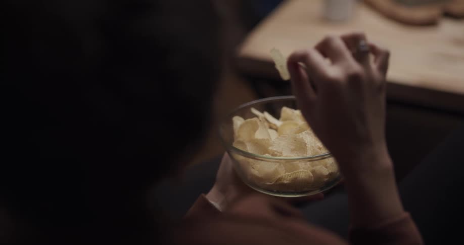 Young woman is eating chips out of a bowl