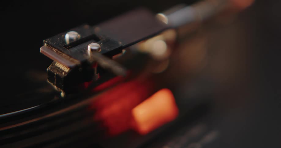 Record player arm drops on to vinyl record rotating on the turntable