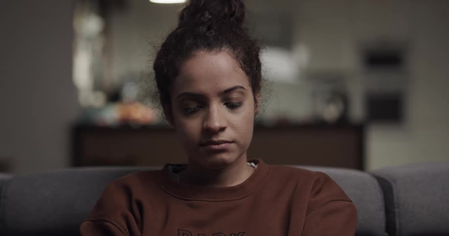 A woman is sitting on a couch in her house