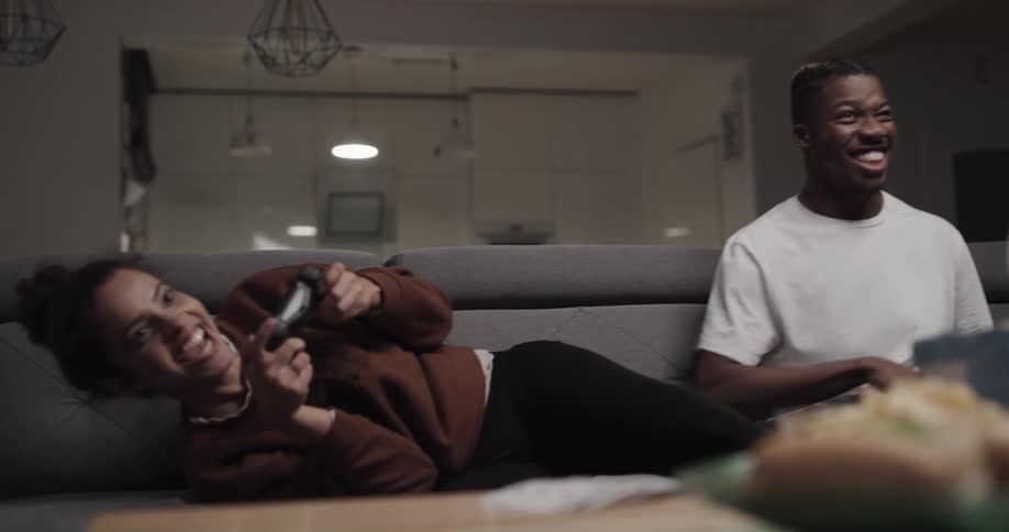 Young couple have fun playing video games sitting in the couch at home