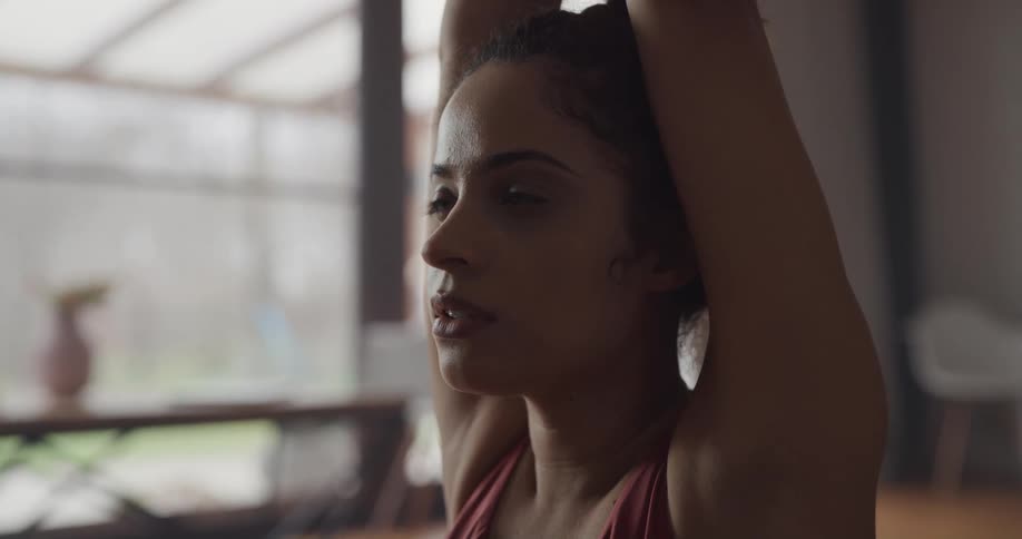 A woman practices yoga indoors during the day