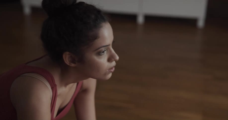 Woman wearing sports clothes practices yoga in the living room at home