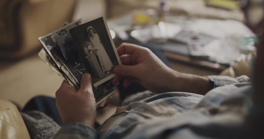 Man sitting on a couch at home looking at old black and white photos
