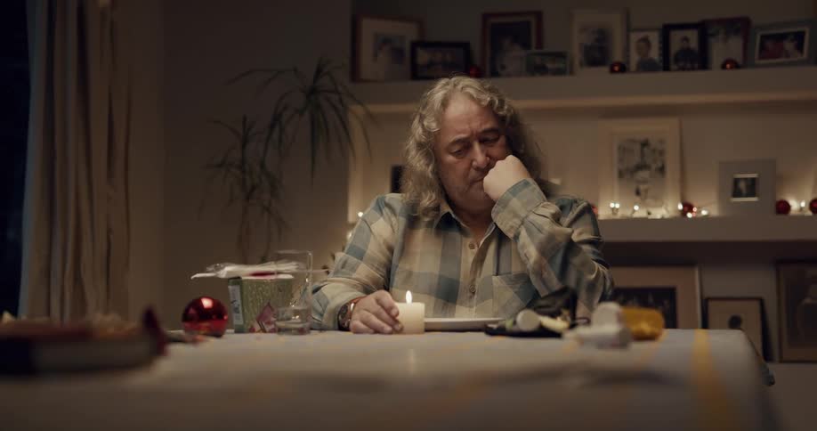 A man is sitting at his table and looking at a candle