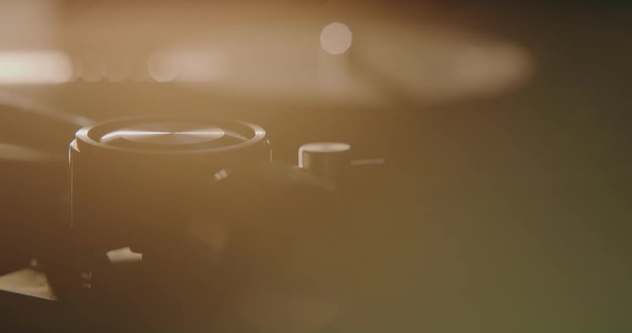 Close up of the arm of a turntable moving close to a spinning vinyl record