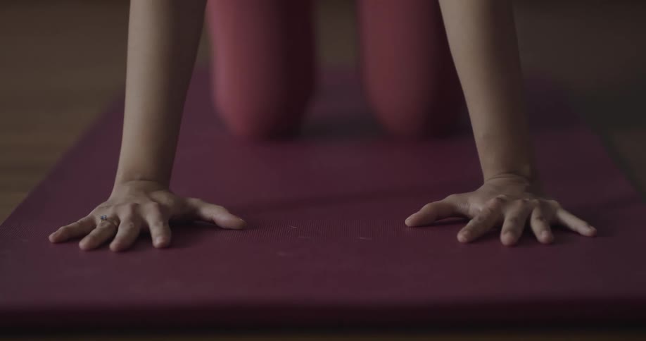 A person practices yoga on a yoga mat indoors