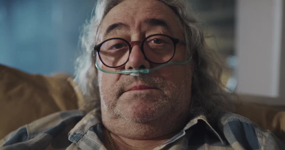 A sick man has a breathing tube in his nose