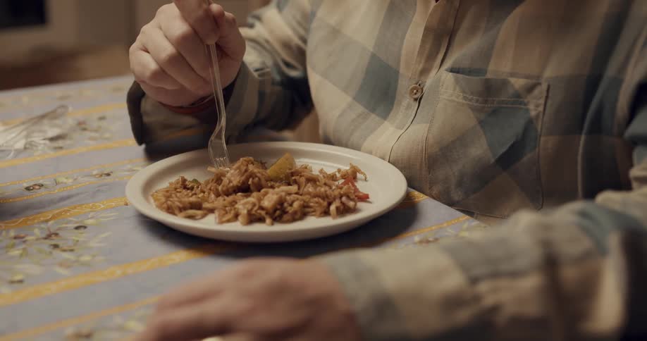 Old man is sitting at the table and eating food