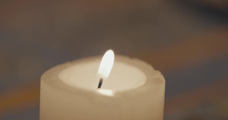 Close up of the handof a person using a match to light the flame of a candle