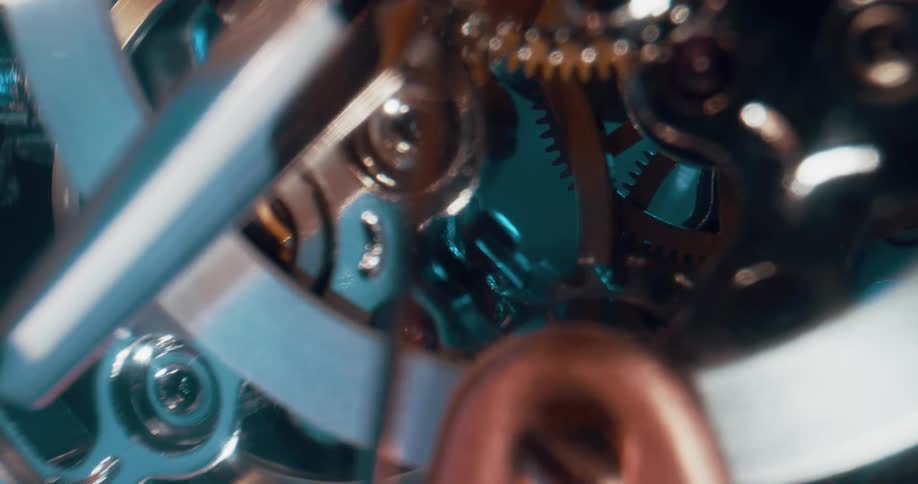Light shines on gears and wheels inside a mechanism as they turn
