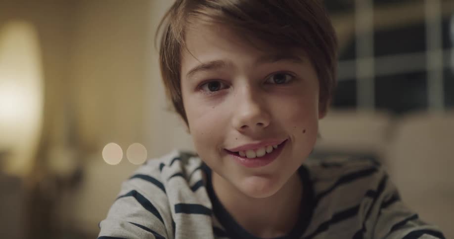 A child is smiling and sitting in a room