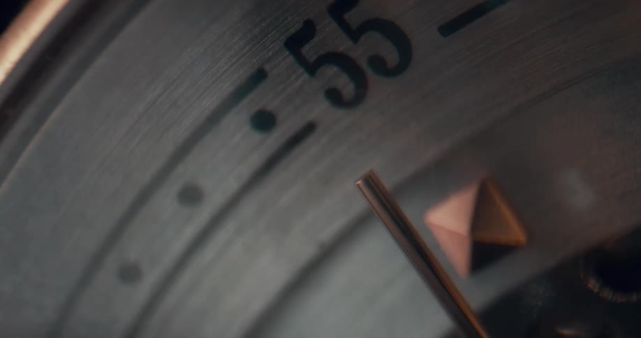 Clock arm moving over the steel dial of an analog clock