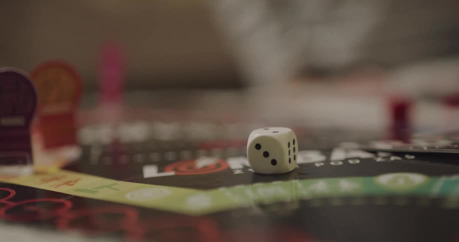 A child reaches for and rolls the die while playing a board game