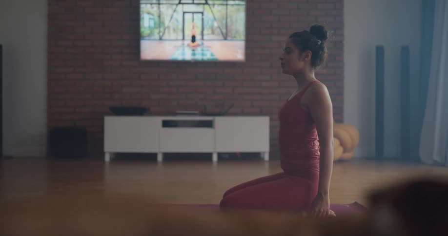 A woman is doing yoga and stretches indoors