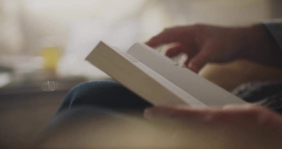 Man sitting on a couch at home reading a book