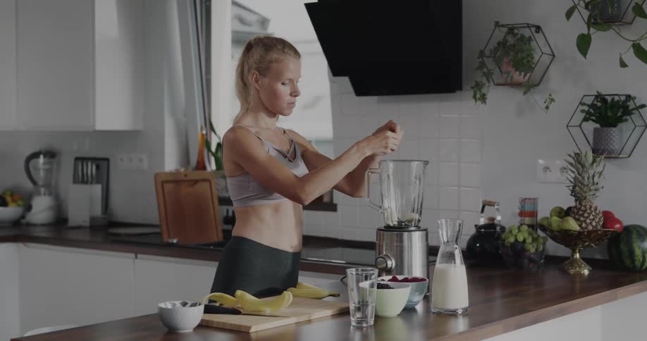 A woman is making a smoothie in her kitchen