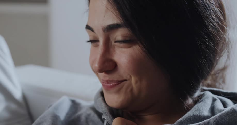 A woman sits on a couch and laughs as she talks
