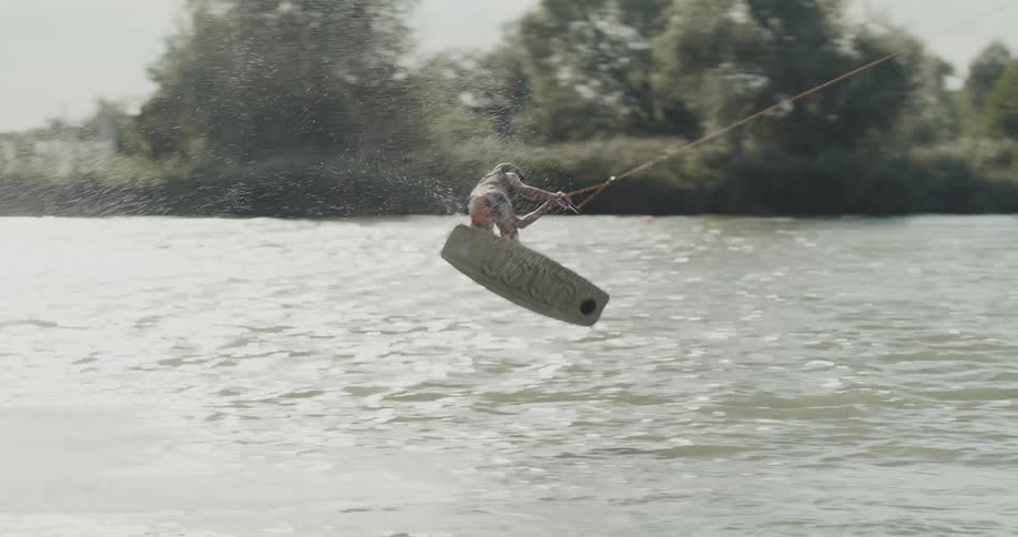 A person rides a wake board and does a twisting jump in the air