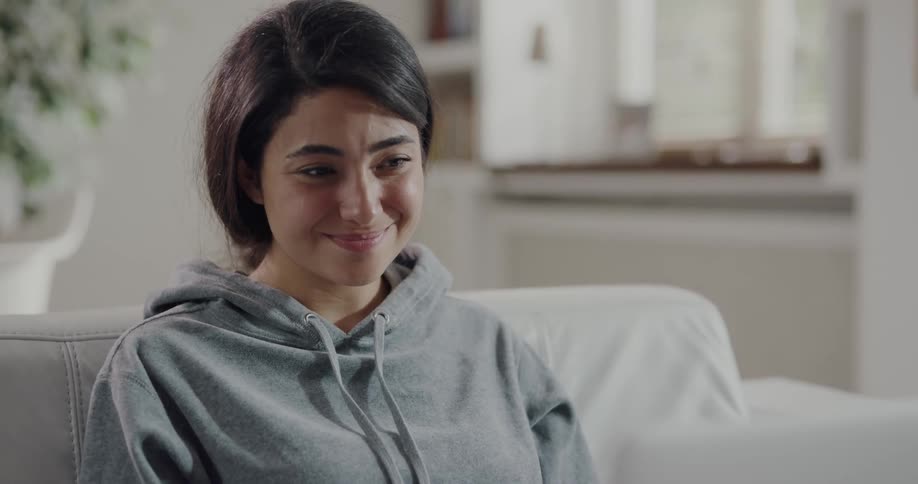 A woman smiles and laughs while participating in a video chat using a laptop
