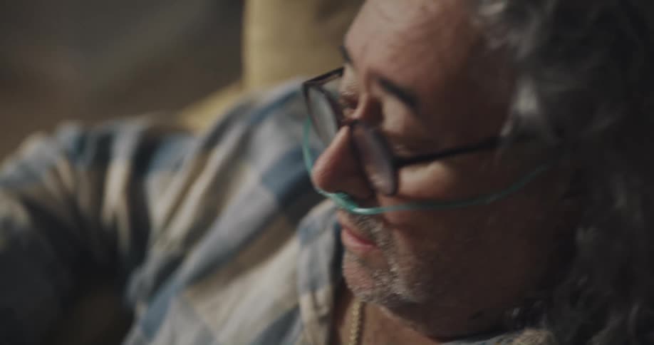 A man grabs his chest as he coughs then reaches for a glass of water