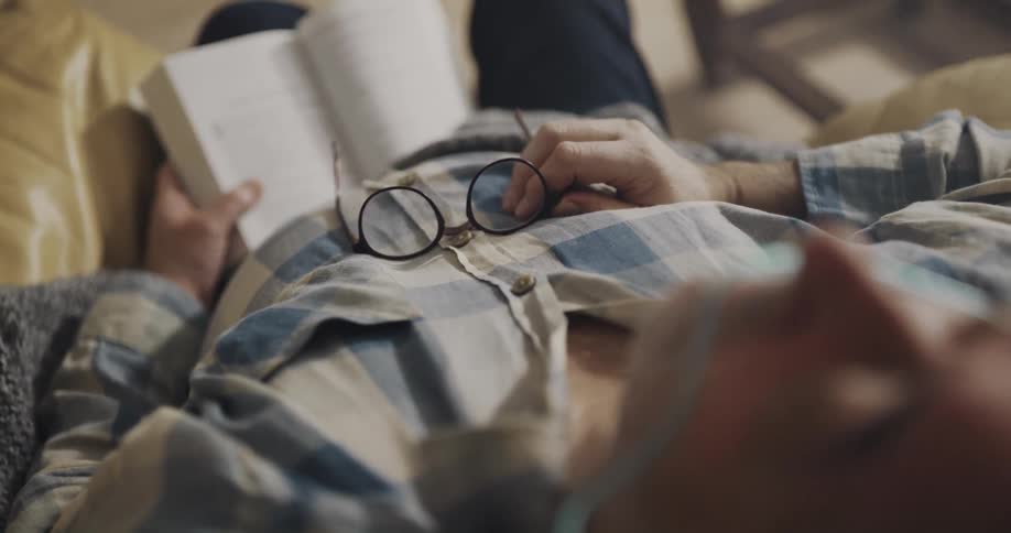 A man is sleeping with a book in his lap