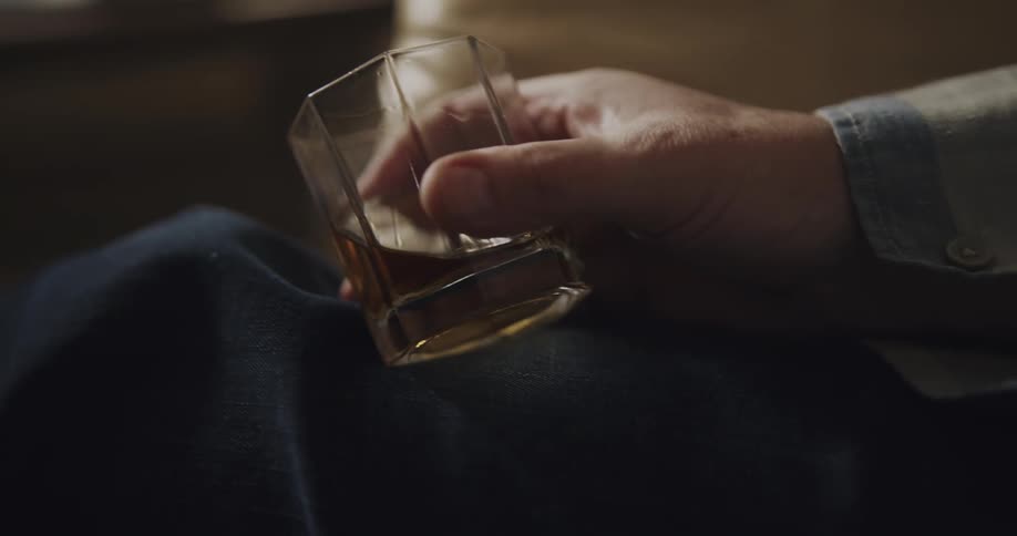 A view of a person holding a glass of alcohol