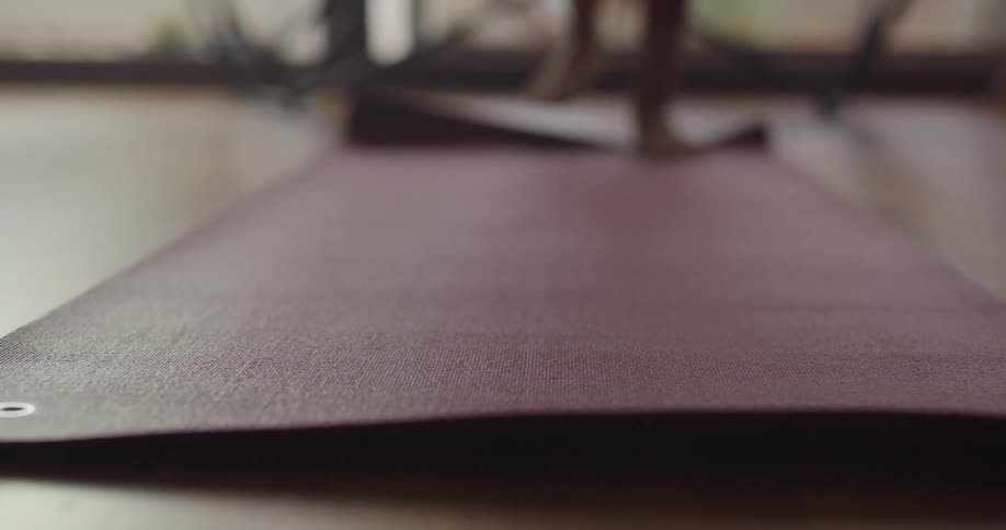 A woman is standing on a yoga mat indoors
