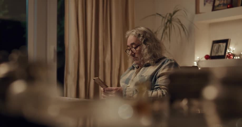 A man is sitting at a table and texting on his cellphone