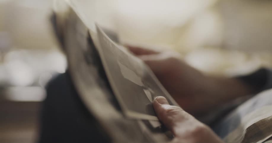 Man sitting on a couch at home looking at old black and white photos
