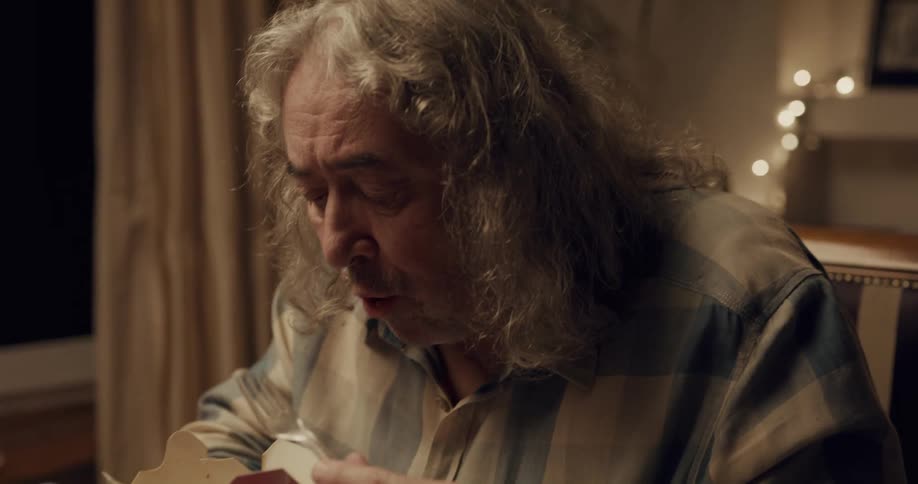 Long haired mature man eating asian takeout food at home alone