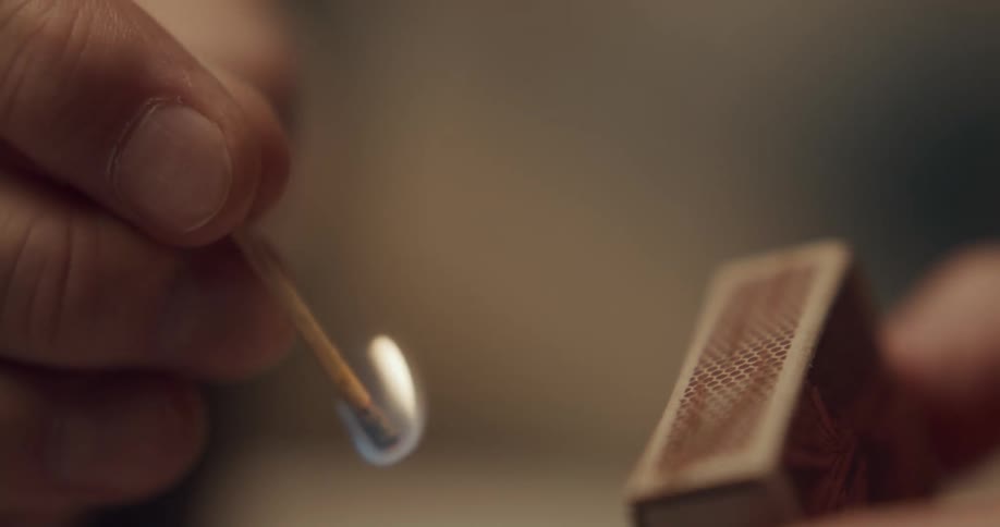 Close up of person striking a match from a matchbox
