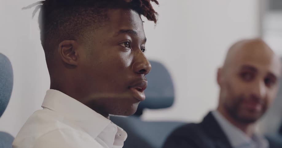 A man speaks while sitting around a table with coworkers in a meeting