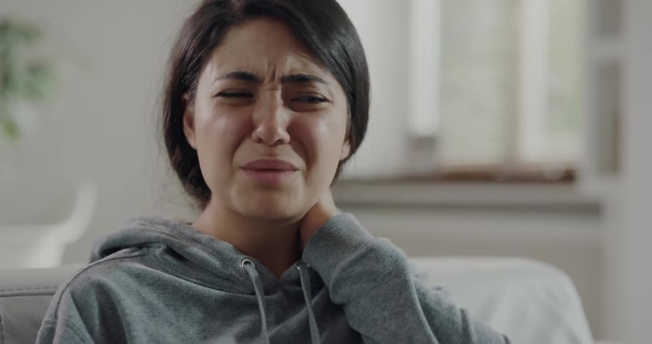 A woman rubs her neck in pain