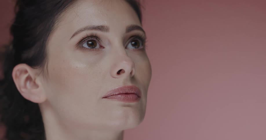 A woman is standing by a pink colored wall