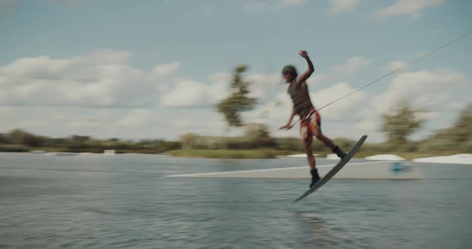 A man does a jump and flip on the wakeboard