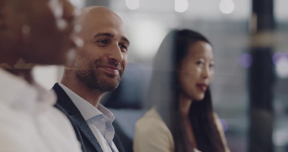Coworkers smile as one of them talks while sitting in a meeting