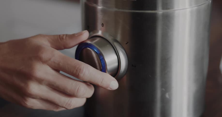 Woman turns the knob on a blender in the kitchen