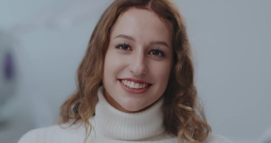 A young woman raises her gaze to smile into the camera